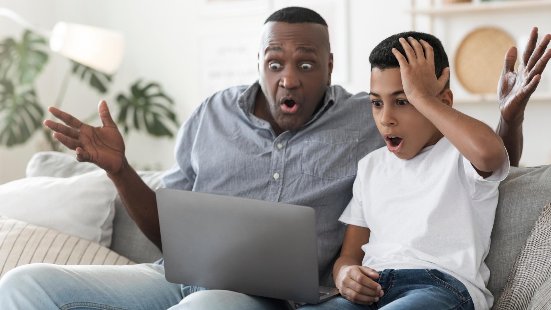 Pai e filho surpresos diante de um notebook
